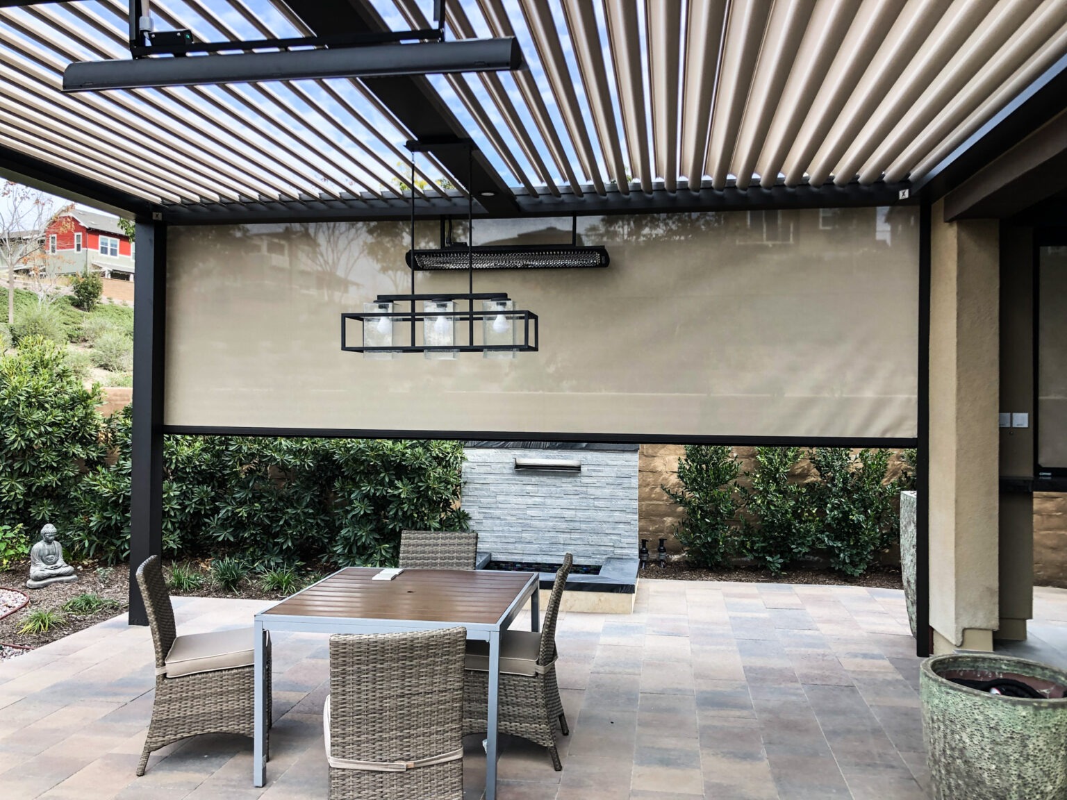 Outdoor patio area with a covered pergola, patio furniture, and a stone wall. 